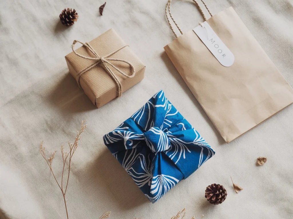 Three examples of eco friendly gift wrapping: kraft paper with twine, fabric wrap, and recycled paper gift bag